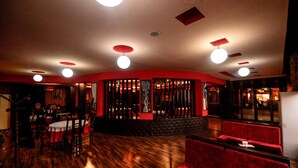 A restaurant with wooden flooring, red upholstered seating, and a brick wall.