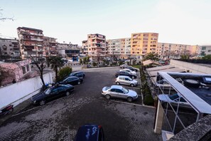 A parking lot with several cars, surrounded by multi-story residential buildings.