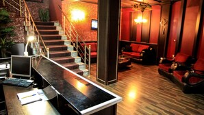 A lobby with a reception desk, a staircase, and red seating area.