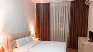 A hotel room with a bed, bedside tables, a desk, and a TV.