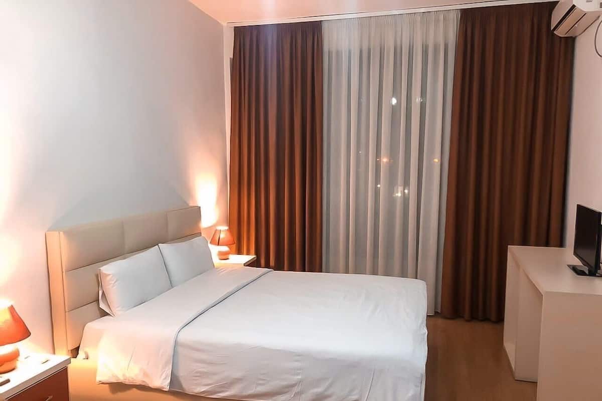 Ett hotellrum med en säng, sängbord, ett skrivbord och en tv.