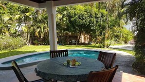A round table with chairs and a pool in the background. - Private villa apartment with pool and within 15 minute walk to 3 beaches. (Bon Accord)