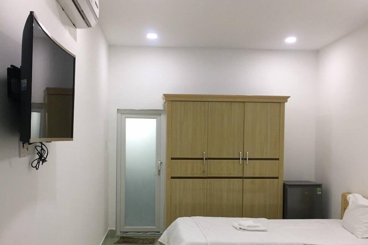 Une chambre d’hôtel avec deux lits, une armoire, un téléviseur et un appareil de climatisation.