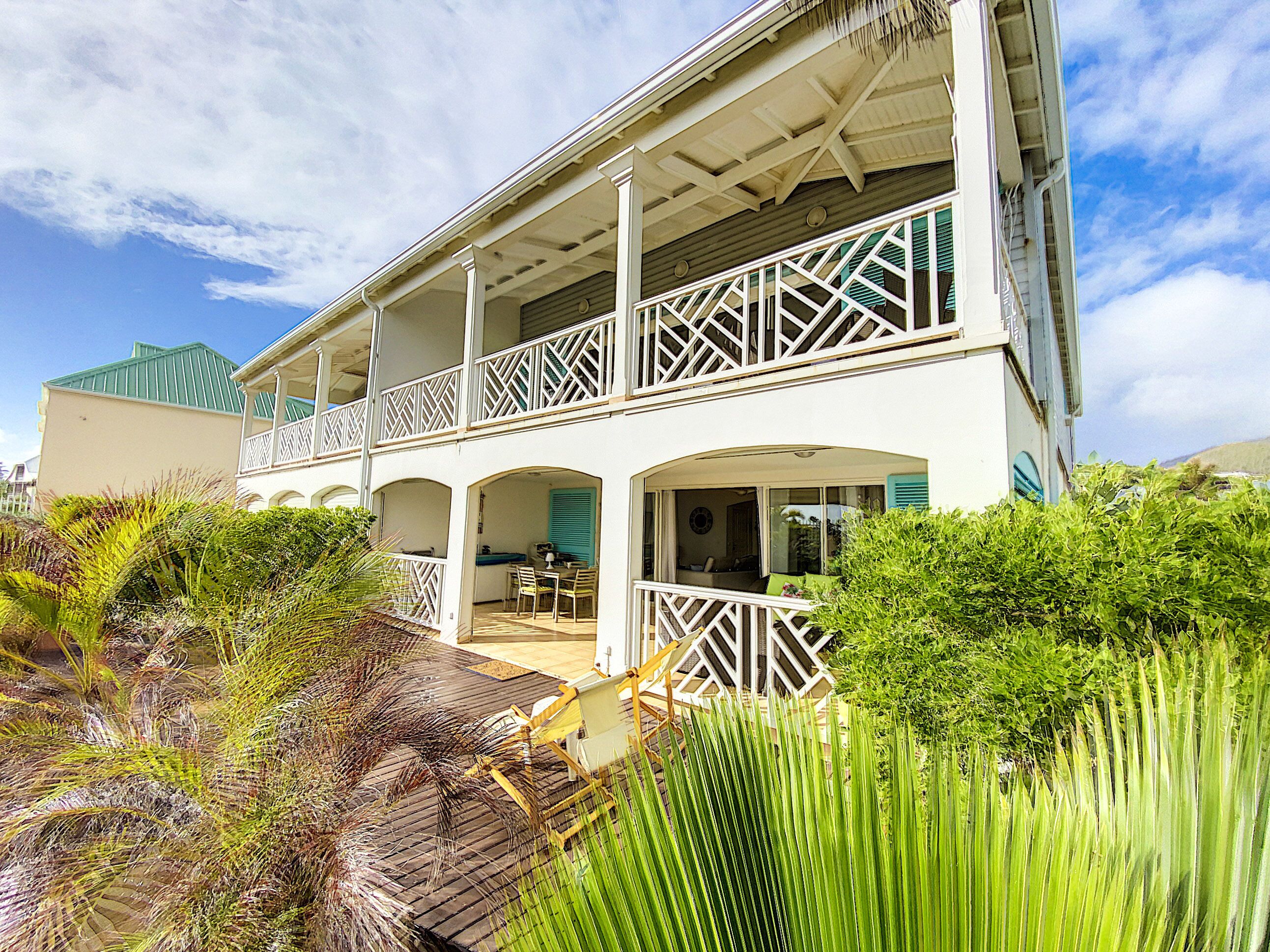 A two-story building with a balcony, a covered patio, and a view of the surrounding greenery.