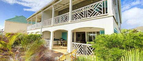 A two-story building with a balcony, a covered patio, and a view of the surrounding greenery.
