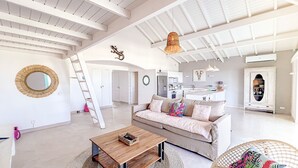 A spacious living area with a high ceiling, a wooden coffee table, a sofa with colorful pillows, and a wicker chair. - Princess Manon, Beachfront, Feet in water,  Ocean view, Pool (Saint-Martin)