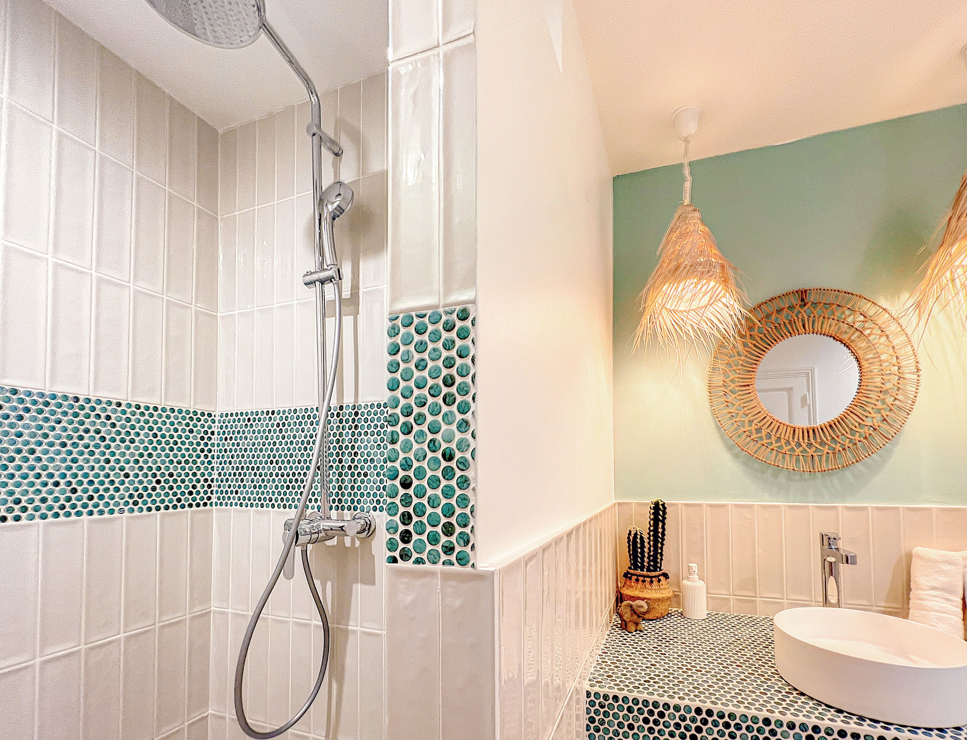 A bathroom with a shower, a sink, and a mirror.