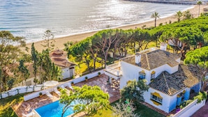 A coastal property with a swimming pool, beach access, and a view of the sea.