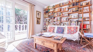 A cozy reading room with a large bookshelf, a comfortable sofa, and a wooden coffee table.