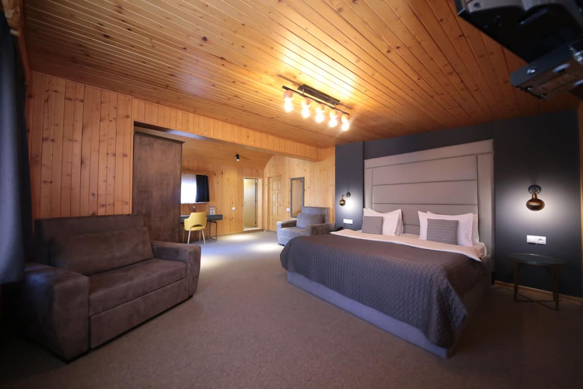 A cozy room with a large bed, a sofa, and a desk.