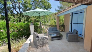 A covered patio area with wicker furniture, a table, and a green umbrella. - Charming Provencal villa in the heart of the forest and  the village of Lorgues (Lorgues)
