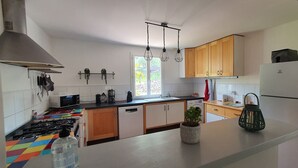 A modern kitchen with white cabinets, a gas stove, a microwave, and a refrigerator. - Charming Provencal villa in the heart of the forest and  the village of Lorgues (Lorgues)