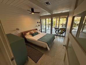 A bedroom with a bed, a ceiling fan, a window, and a view of the outside. - Mid-Century Meets Boaters’ Dream (Siesta Key)