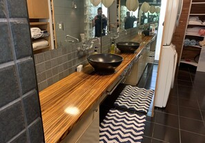 A modern bathroom with a wooden vanity, two large sinks, a mirror, and a towel rack. - Mid-Century Meets Boaters’ Dream (Siesta Key)
