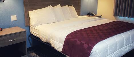 A hotel room with a bed, bedside tables, and a wall-mounted lamp.
