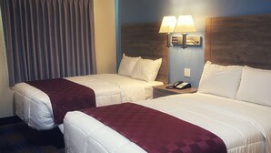 Une chambre d’hôtel avec deux lits, une table de chevet avec une lampe et un téléphone.