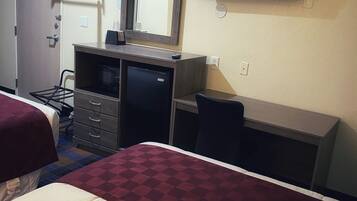 A hotel room with two beds, a desk, a dresser, a mirror, a TV, and a coat rack.