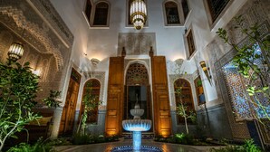 Un patio con una fuente, arcos ornamentales y detalles en azulejos.
