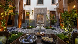 Un patio con una fuente, suelo de baldosas y plantas.