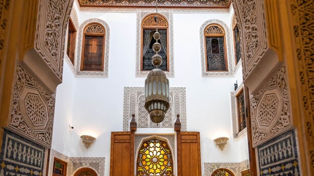 Un patio ornamentado con intrincados trabajos de azulejos, una fuente central y un amplio arco.