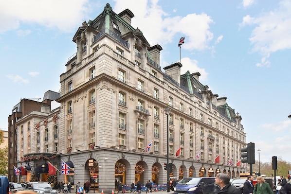 A large, historic building with multiple flags, including the Union Jack, and a prominent entrance with arches.