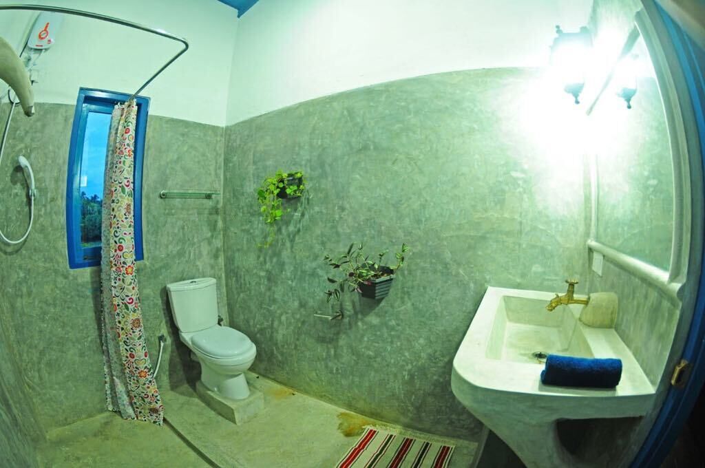 A bathroom with a toilet, a sink, and a shower. There are plants on the wall and a curtain on the door.