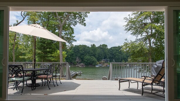 A deck with outdoor furniture and a view of a lake.