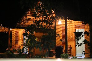 A wooden building with a thatched roof, surrounded by greenery. - Private Organic House (Udawalawa)