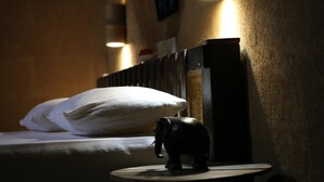 A bed with white pillows and a small elephant figurine on a bedside table.