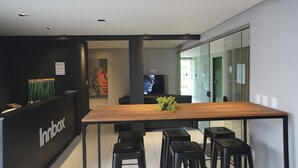 Ein modernes Interieur mit einem Holztisch, schwarzen Hocker, einem Fernseher und einer Wand mit einem 'Innbox'-Schild.