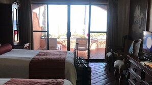 Ein Hotelzimmer mit zwei Betten, einem Koffer, einem Schminktisch und Blick ins Freie.