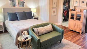 Een slaapkamer met een groot bed, een groene fauteuil, een nachtkastje, een lamp en een kledingkast.