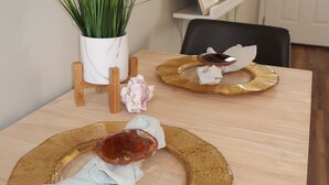 Een eettafel met een plant in pot, een lijst met foto en een decoratief bord.