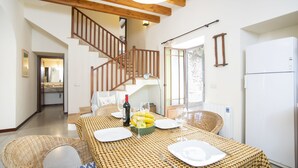 A dining area with a high ceiling, wooden beams, a staircase, and a view of a garden. - Ca Sa Padrina. Tradition and charm in Mallorca (Artá)