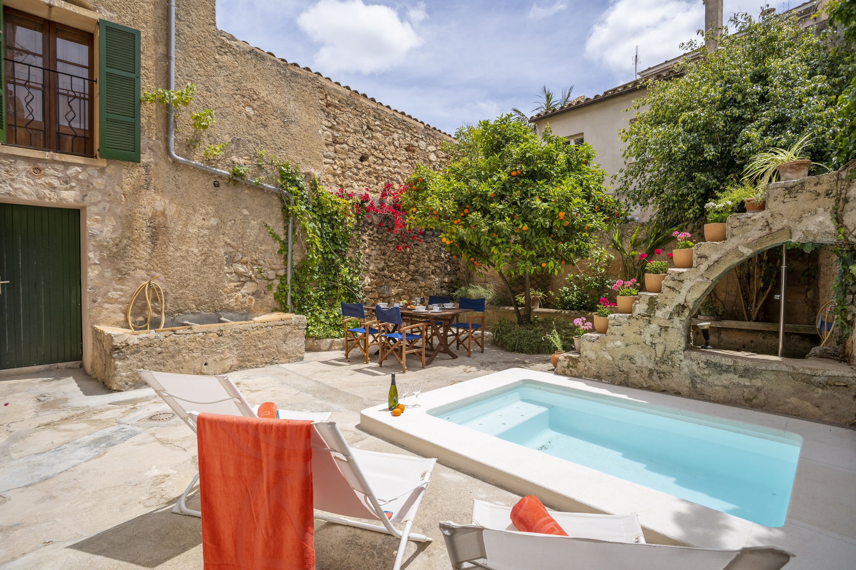 A stone building with a swimming pool, outdoor seating, and potted plants.