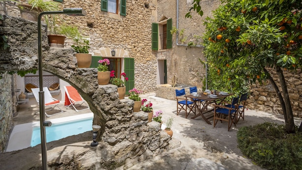 A stone building with a pool, outdoor seating, and potted plants. - Ca Sa Padrina. Tradition and charm in Mallorca (Artá)