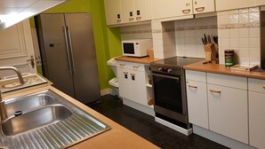 Ett kök med vita skåp, ett kylskåp i rostfritt stål, en mikrovågsugn, en ugn och en diskho.