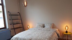 Ett sovrum med en säng i trä, en stege och två bordslampor.