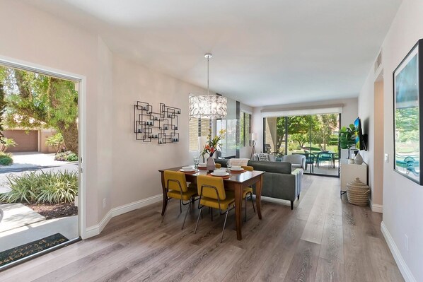 Un espace de repas moderne avec une table et des chaises en bois, un élément décoratif mural et une vue sur la terrasse extérieure.