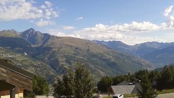 A mountain landscape with a clear sky. There are buildings and trees in the foreground.
