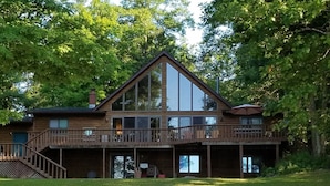 A two-story log cabin with a balcony and a covered deck area. - Round Lake Cabin Retreat (Hayward)