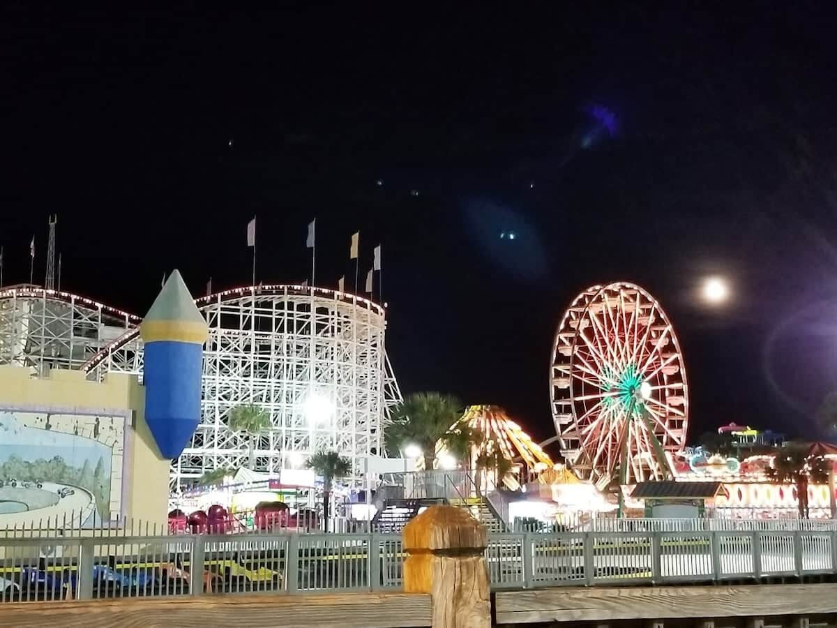 En nattbild av ett tivoli med ett pariserhjul och en bergochdalbana.