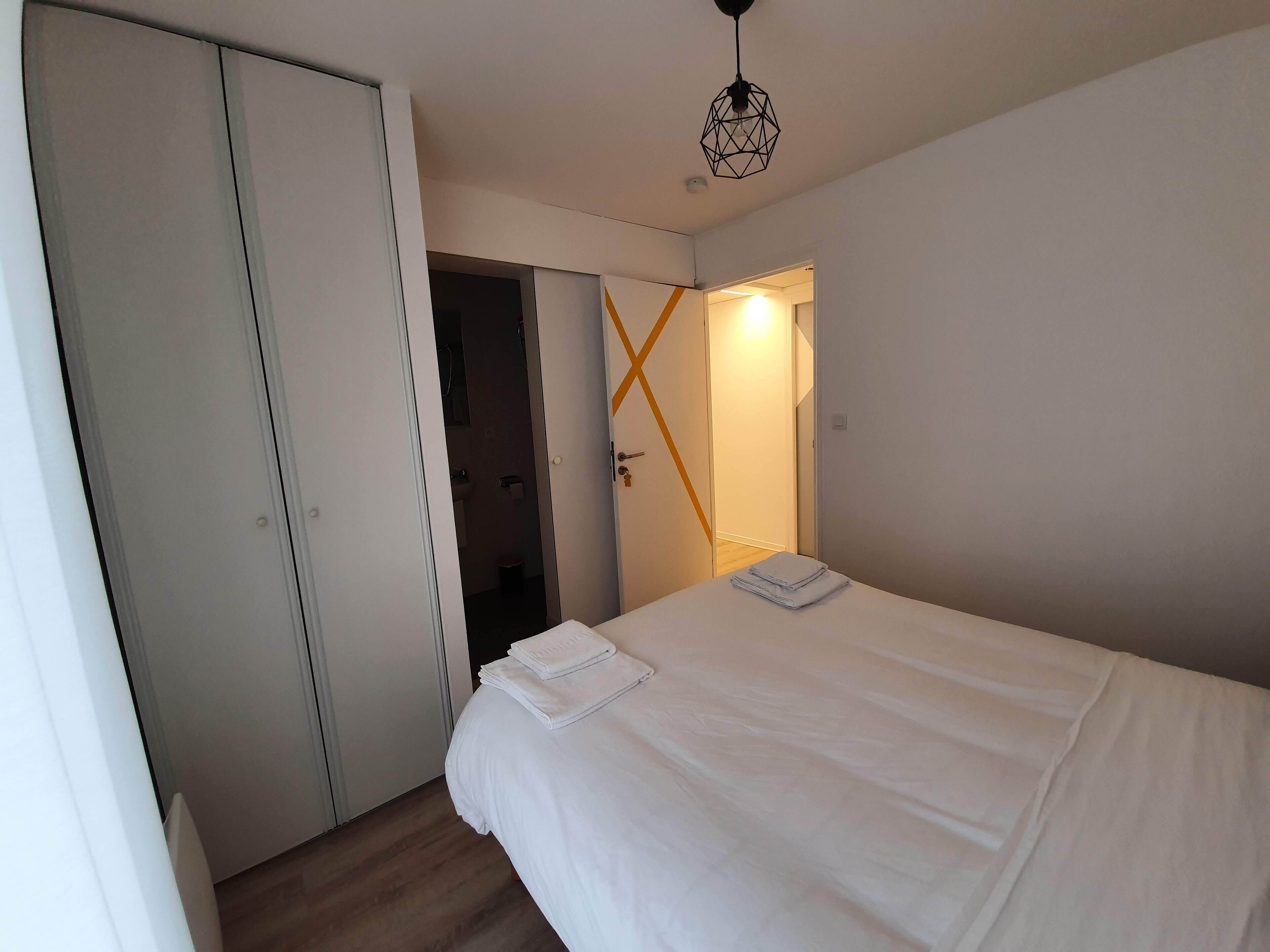 A bedroom with a bed, a wardrobe, and a bathroom visible through an open door.