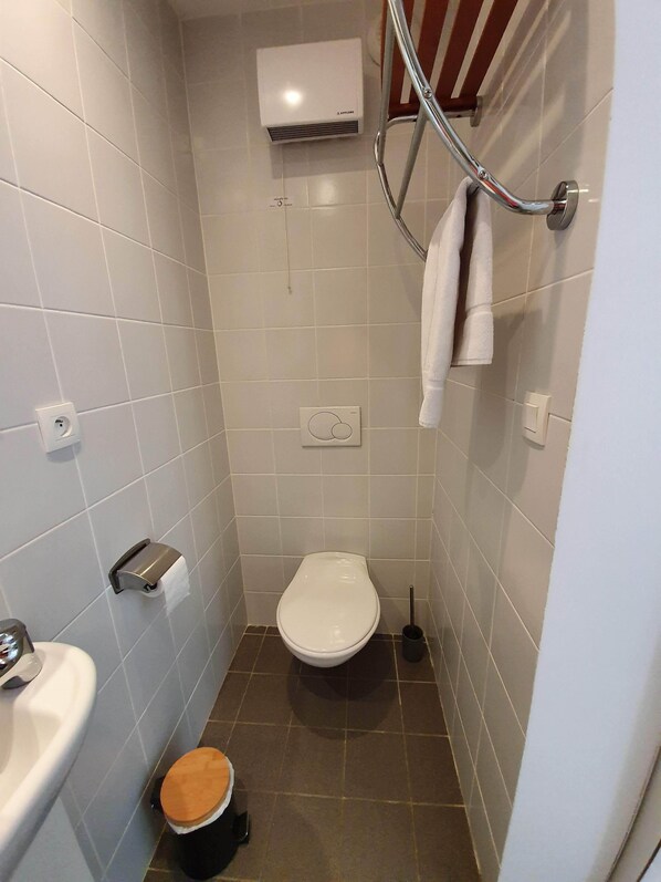 Un baño pequeño y moderno con inodoro, lavamanos y ducha.