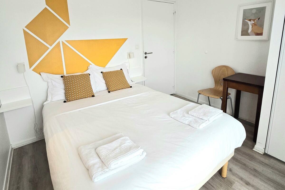 Quarto de hotel moderno com uma cama grande, uma escrivaninha e uma cadeira.