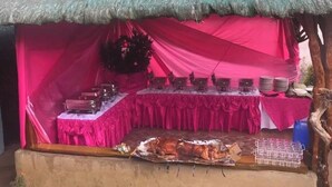 A thatched-roof structure with a pink interior, a table with dishes, and a roasted pig on a table. - Nipa Hut Tagaytay Get Away for Family & Friends (Amadeo)