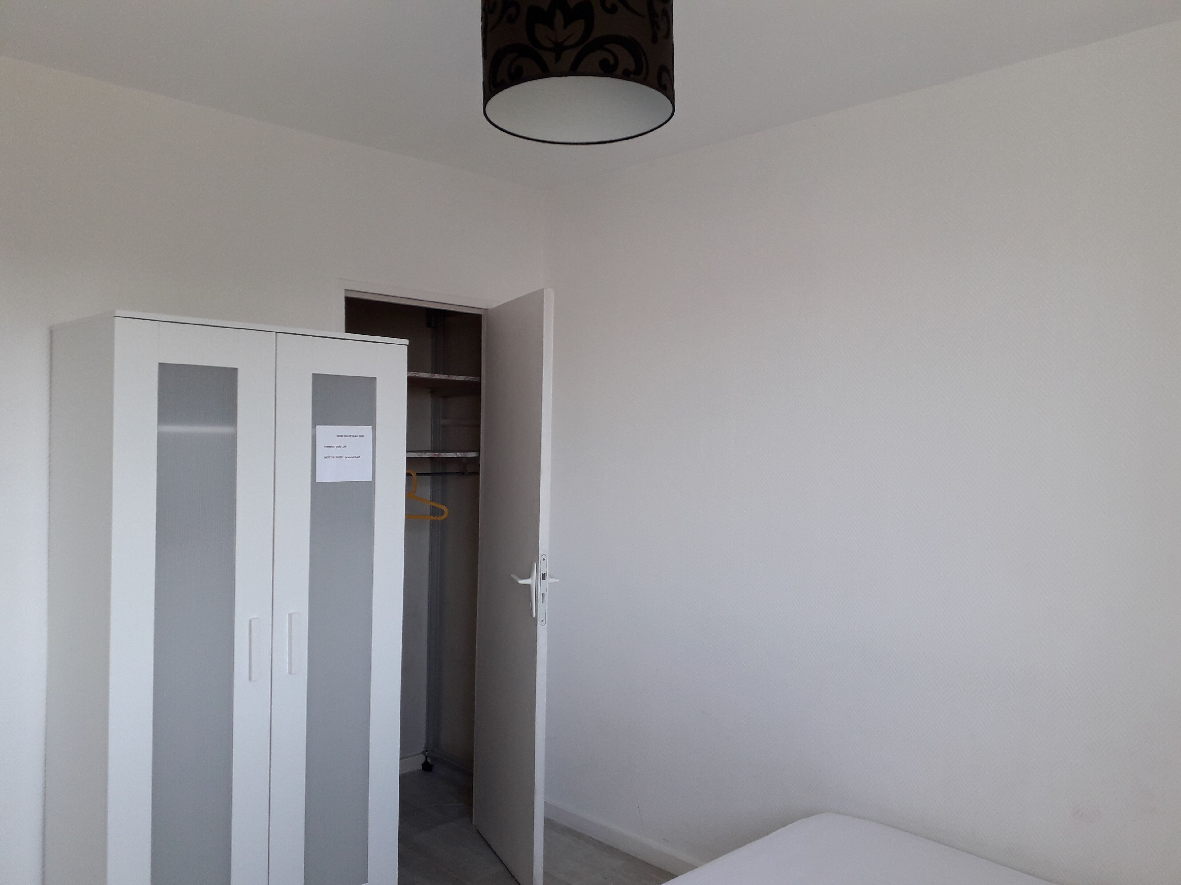 Une pièce avec une armoire blanche, une porte et un porte-manteau mural.
