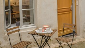 A small outdoor seating area with a wooden table and two chairs, a window, and a door. - !!! COZY APARTMENT 500 FROM THE PALAIS DES PAPES !!! (Avignon)