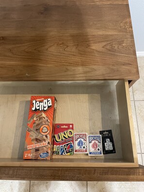 A drawer containing Jenga, UNO, Bicycle cards, and 5 dice.