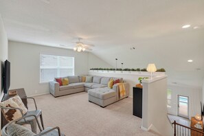 A spacious living area with a sectional sofa, a ceiling fan, and a view of the outdoors. - Family friendly w/ beautiful pool, SPA, and BBQ terrace! (Tomball)